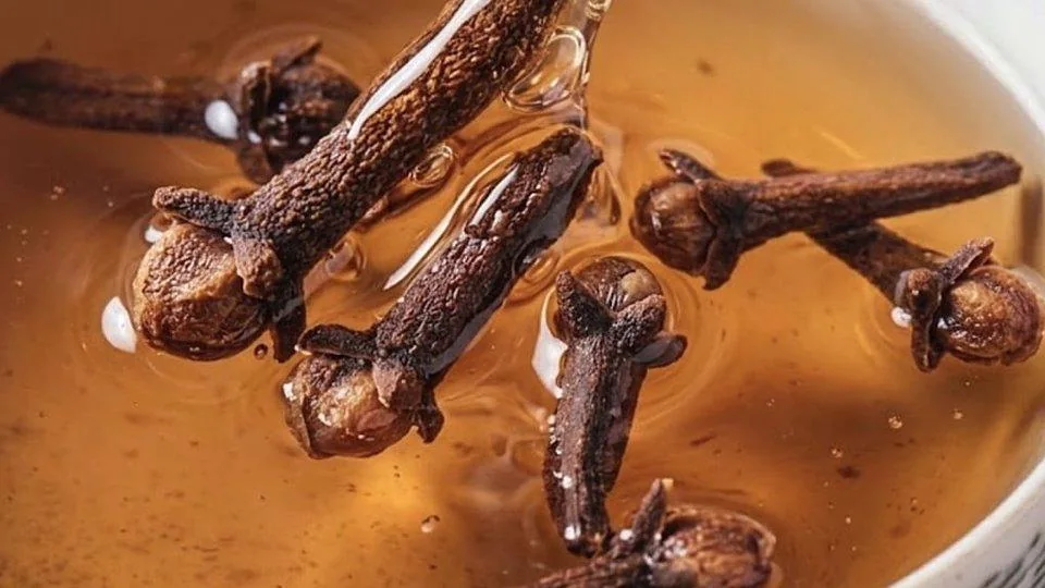 Close-up van kruidnagels in een amberkleurig aftreksel